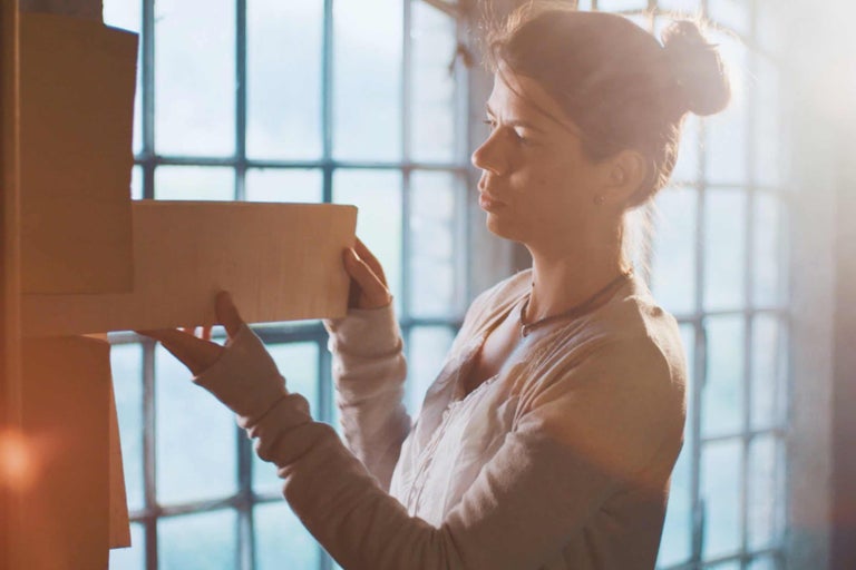 Kvinna hanterar träpaneler framför ett fönster. Gör det själv.