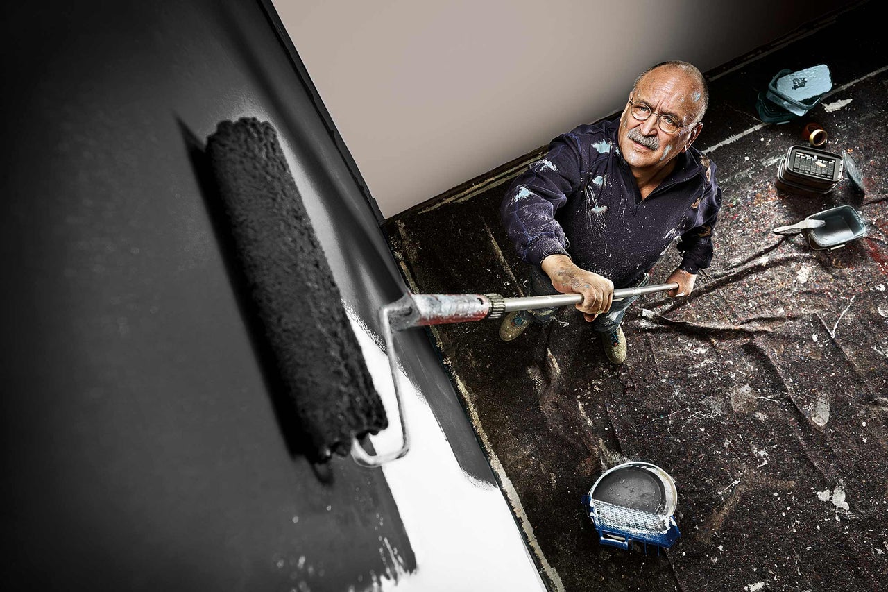 Man målar vägg med färgrulle, renoveringsprojekt