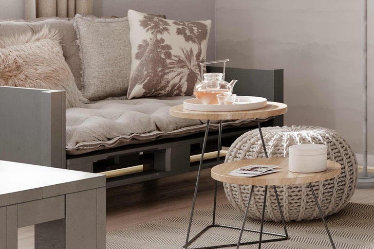 Vardagsrum med pallsoffa, kuddar, sidobord och sittpuff