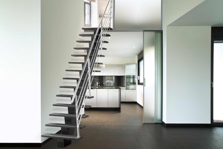 Trappa med stålräck i ett ljust rum med kök