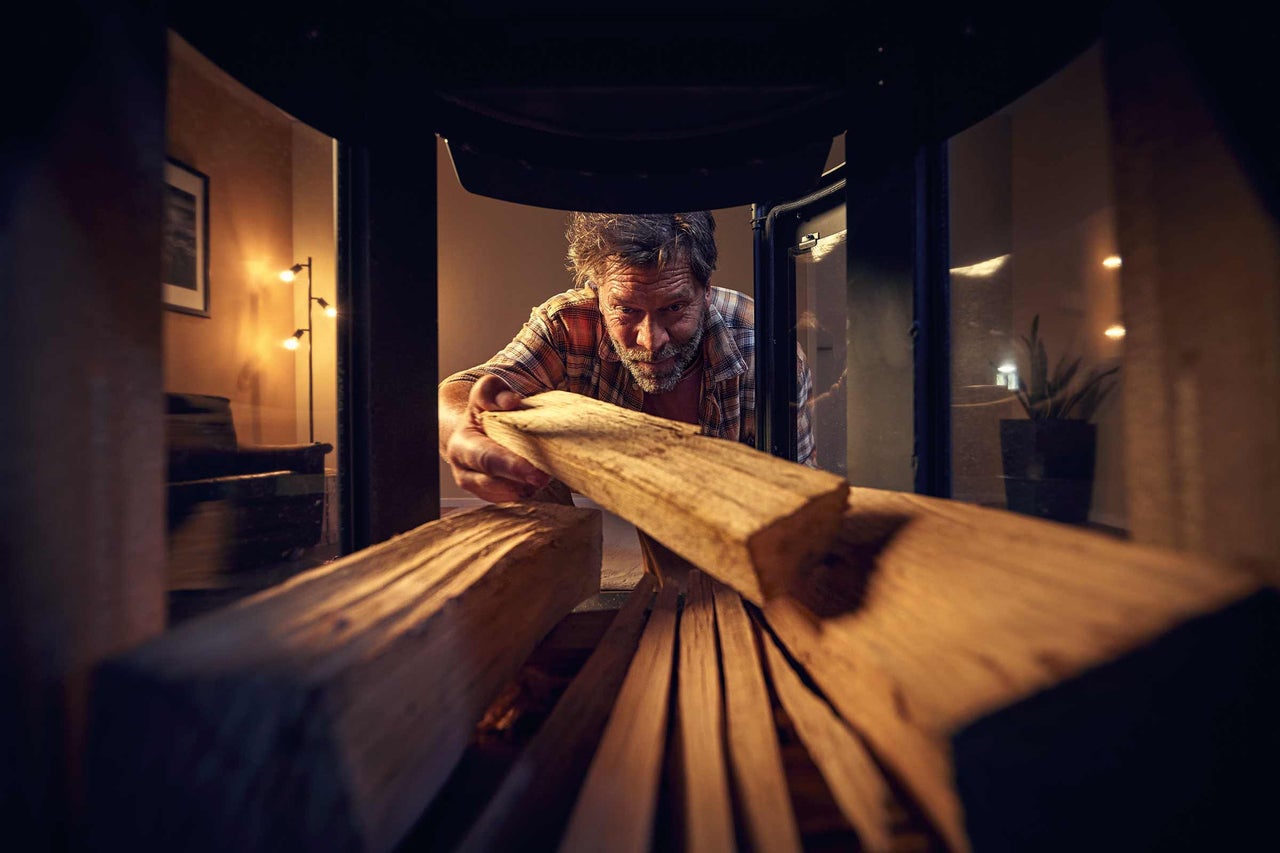 Man lägger ved i en vedeldad kamin