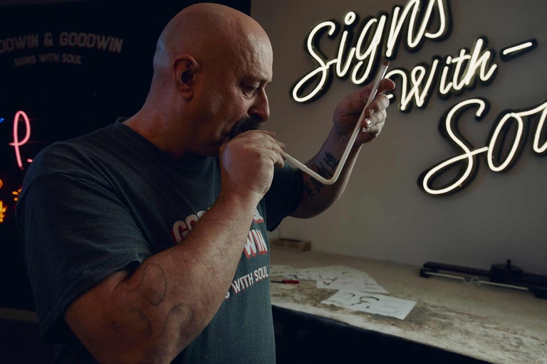 En man formar ett neonrör för en ljusreklam.