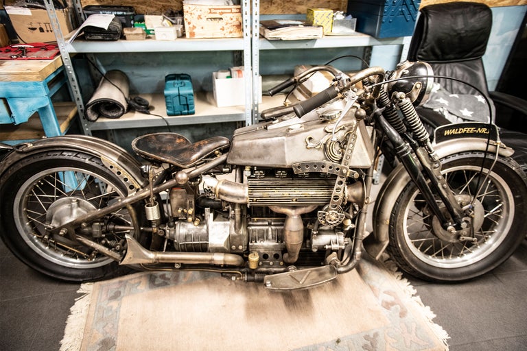 Silverfärgad motorcykel i en verkstad framför en hylla