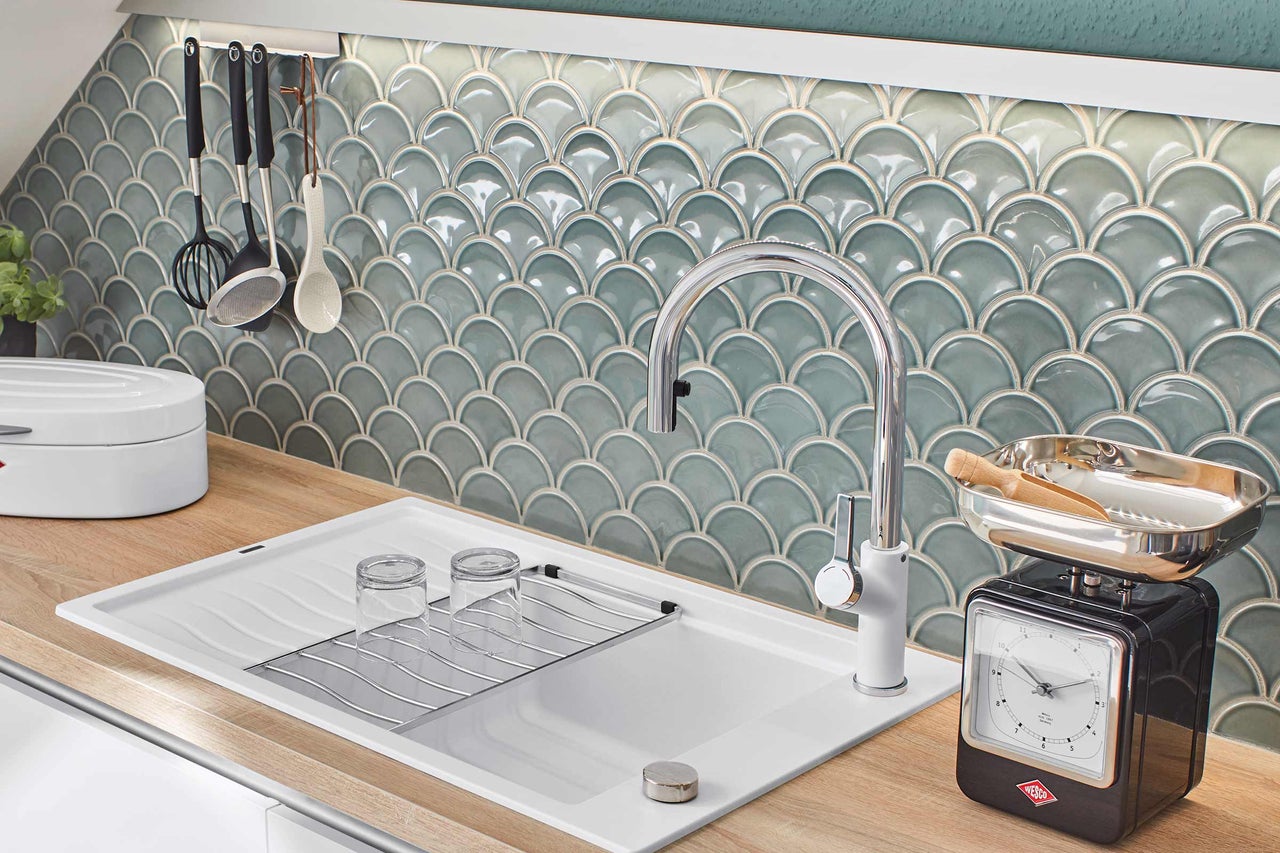 Köksscen med diskho, armatur, handdukshållare, köksredskap och kakel