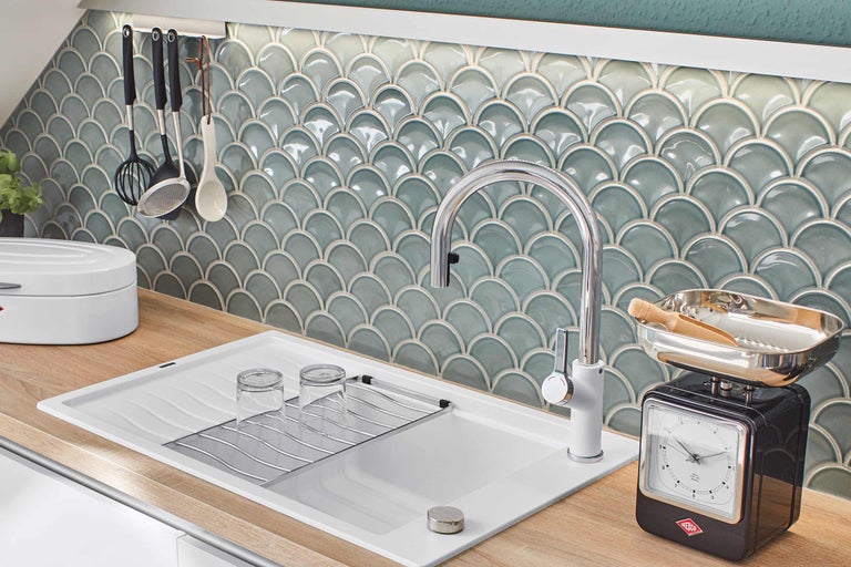 Köksscen med diskho, armatur, handdukshållare, köksredskap och kakel