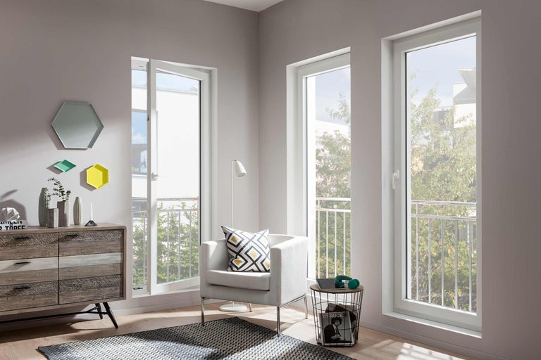 Ljust vardagsrum med vita plastfönster, fåtölj och byrå