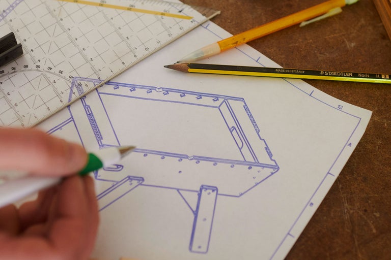 En konstruktionsritning med penna, triangel och skärkniv