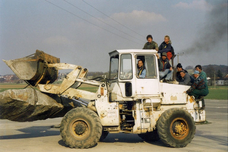 Hjullastare med stenar och flera personer