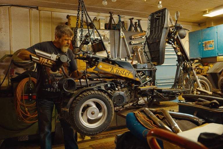 Verkstadsscen med en person som arbetar på en skoter som hänger i en kedja