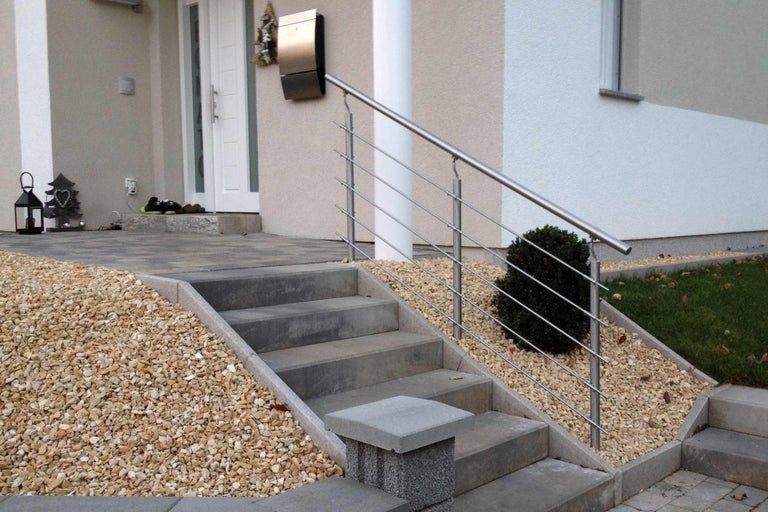 Utomhustrappa i betong med räcke i rostfritt stål framför ett hus
