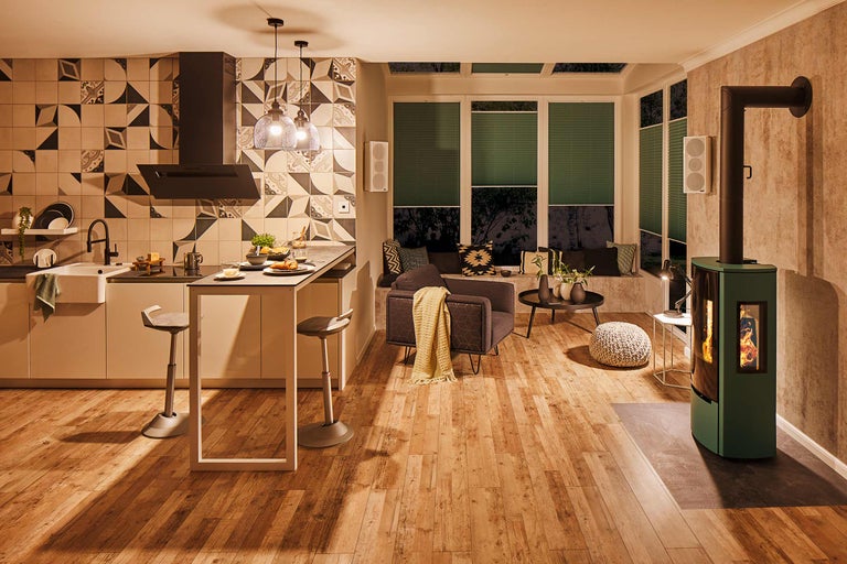 Vardagsrum med kök, sittplats vid fönstret, fåtölj och kamin