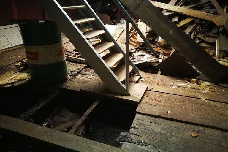 Vindsutrymme med trappa, trärester och oljefat