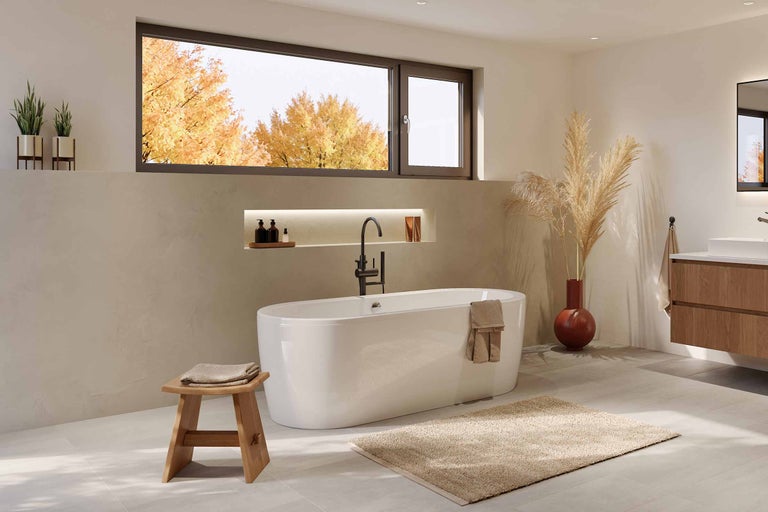 Ljust badrum med fristående badkar, träpall och fönster