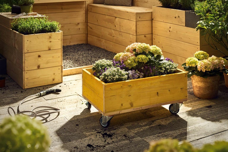 Scen med upphöjda rabatter i trä och olika växter på en terrass.