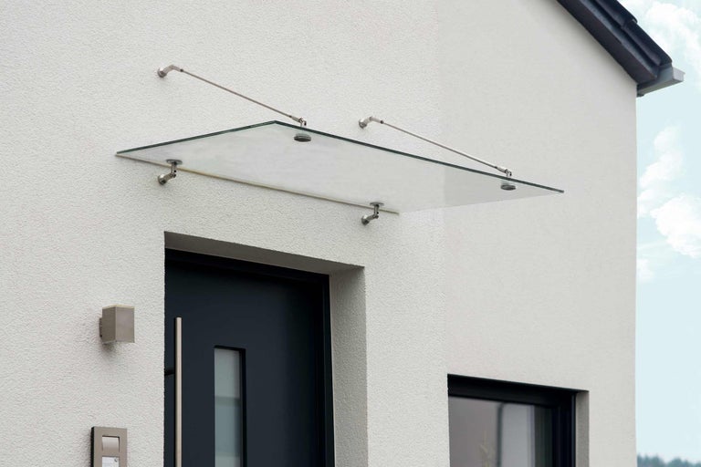 Glasstak över en ytterdörr med rostfria fästen på en husvägg