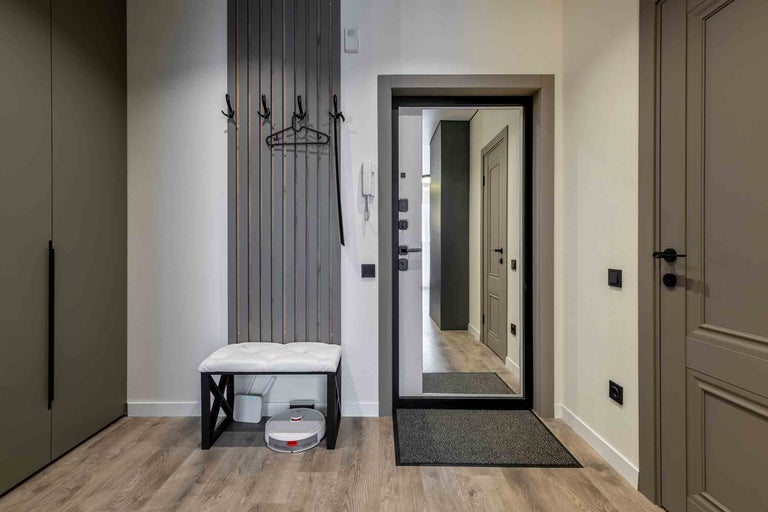 Entré med garderob, bänk, spegel och robotdammsugare.