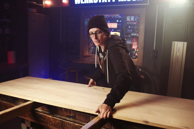 En person arbetar med en träskiva i en verkstad.