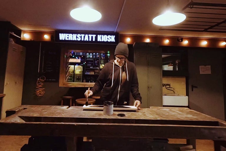 Kvinna målar en träplanka i en verkstad.