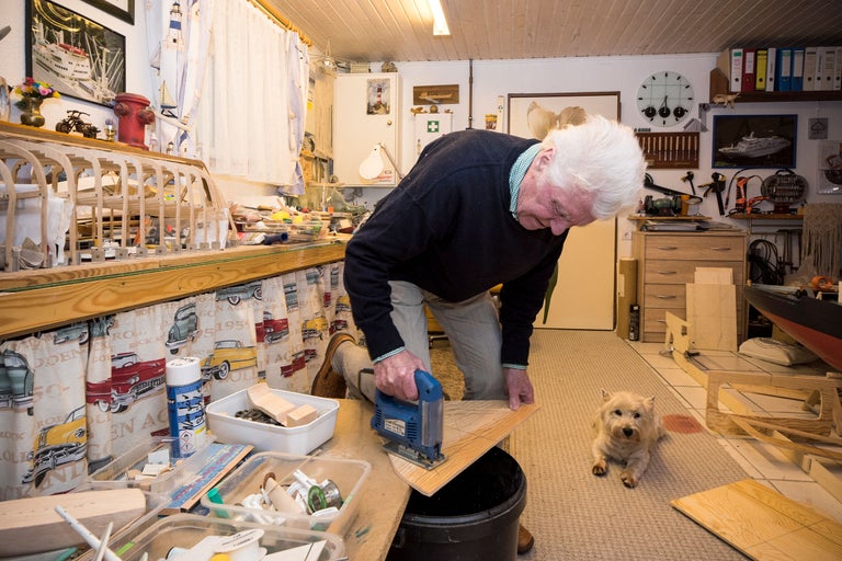 Man arbetar med sticksåg i verkstad, hund ligger på golvet