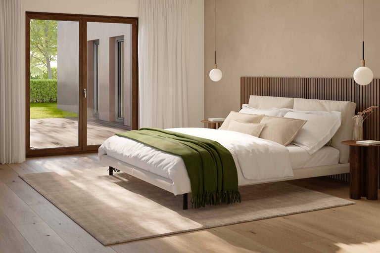 Ljust sovrum med säng, sängbord, matta och altandörr