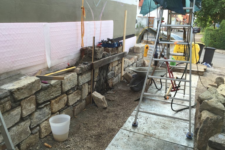 Byggarbetsplats med stenmur, stege och verktyg