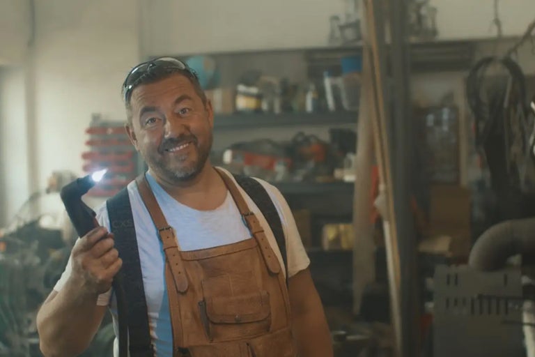 En man med pannlampa och läderförkläde i en verkstad.