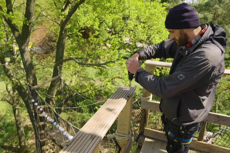 Man arbetar med en borrmaskin i en trädkronvandring