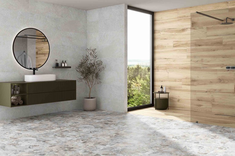 Ljust badrum med handfat, spegel, kakel med stenimitation och duschkabin.