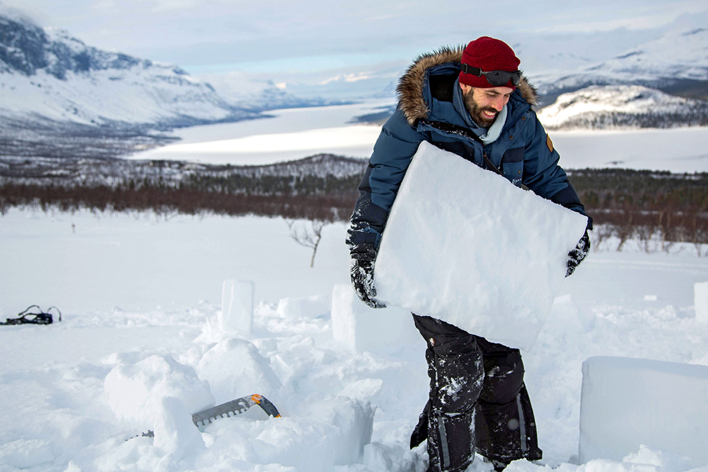 Man bär ett isblock i ett snöigt vinterlandskap.