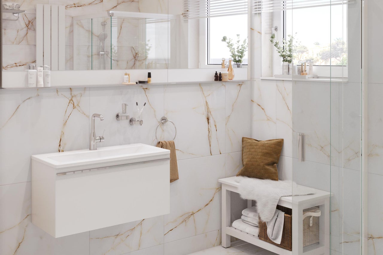 Ljust badrum med tvättställ, spegel, handdukshållare och bänk framför marmorvägg