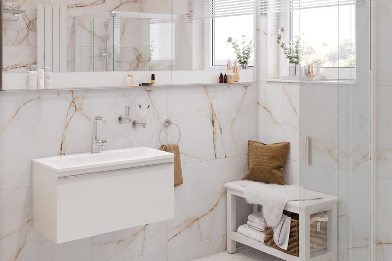 Ljust badrum med tvättställ, spegel, handdukshållare och bänk framför marmorvägg