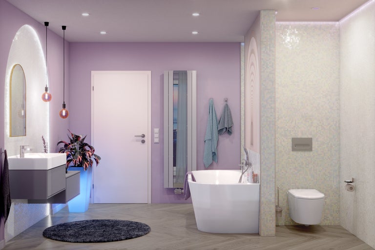 Modernt badrum med lavendelfärgade väggar, fristående badkar, vägghängd toalett, grå kommod och golv i träoptik.
