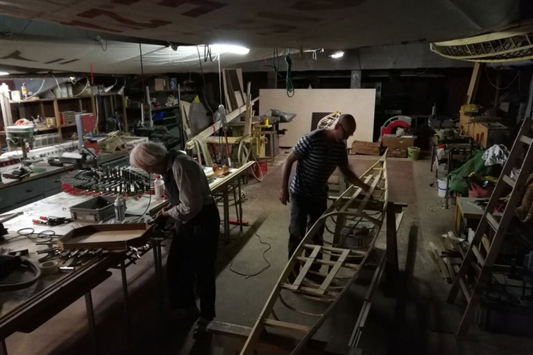 Verkstad med personer, träbåt och verktyg