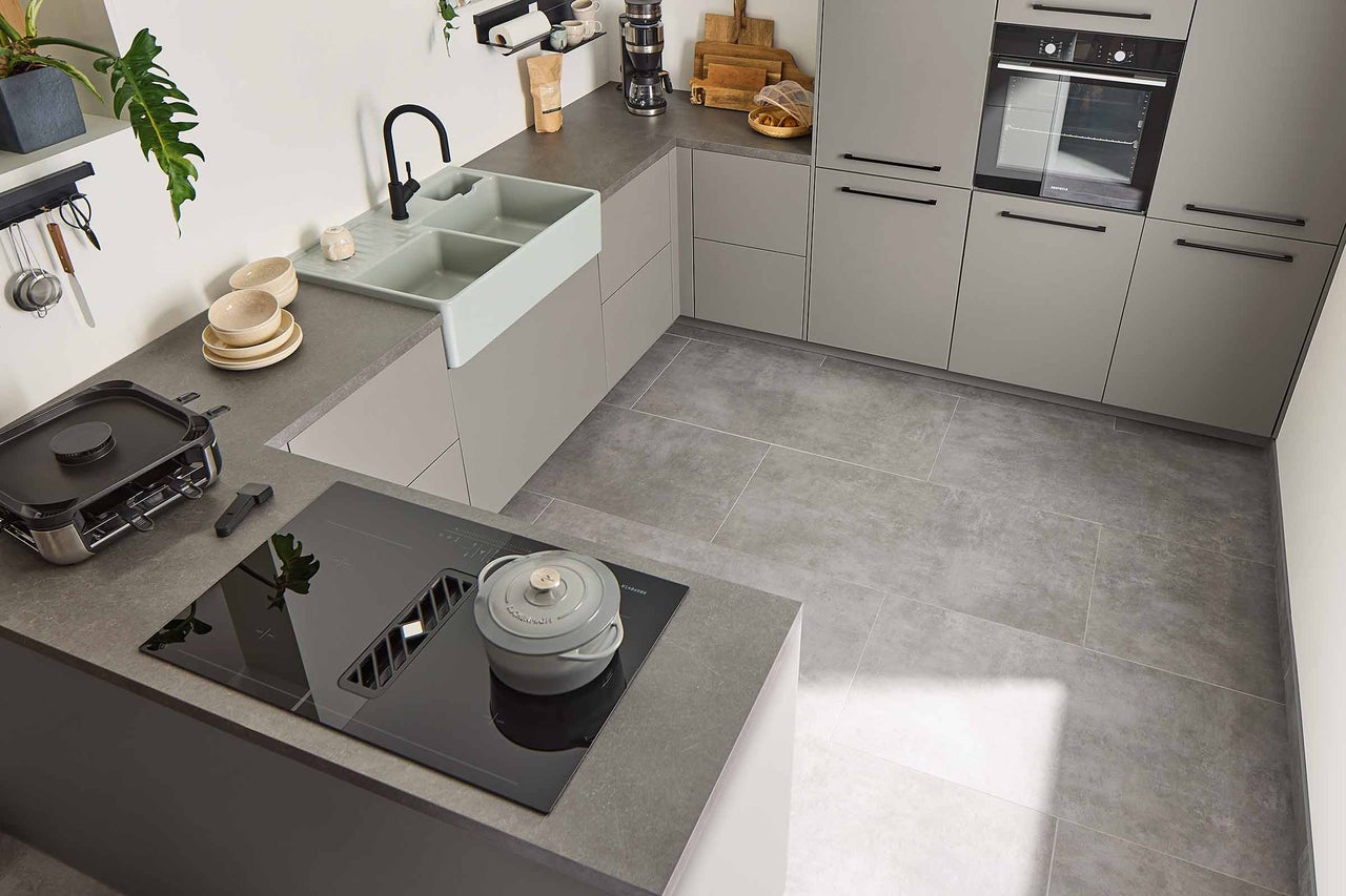 Ljust kök med diskho, spishäll, fläkt, ugn och köksredskap.