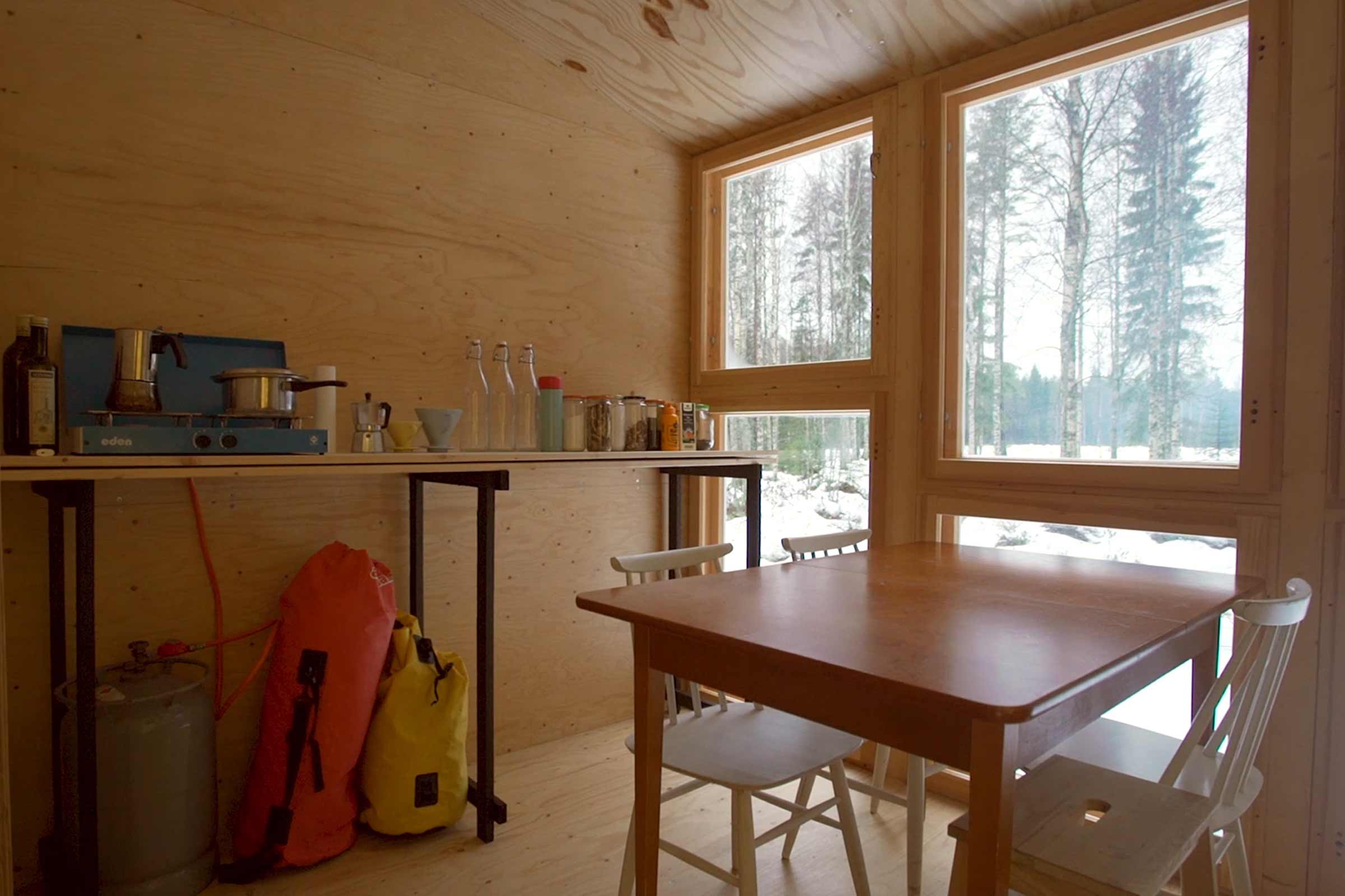 Interiör av ett rum med bord, stolar och hyllor framför fönstret.