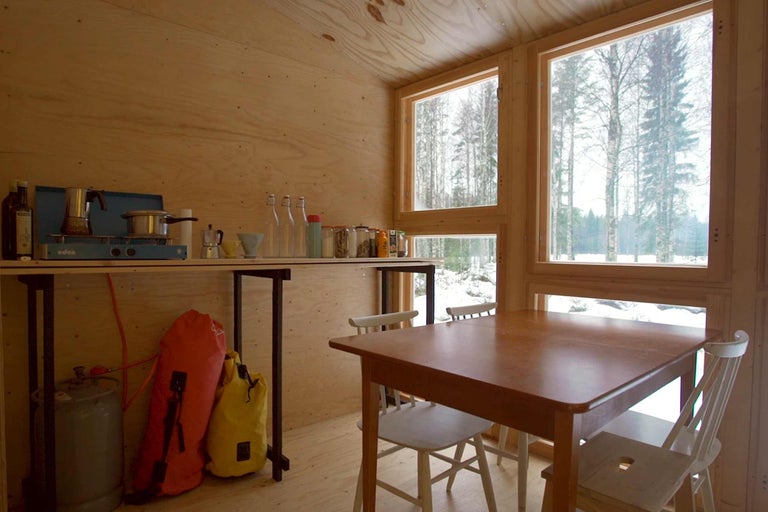 Interiör av ett rum med bord, stolar och hyllor framför fönstret.