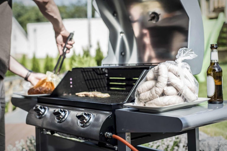 Grillscen med grill, korv och person med grilltång