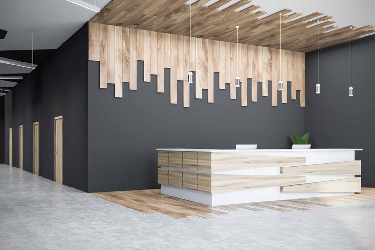 Kontorslobby med träpanel, reception och pendellampor.