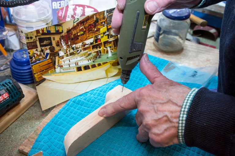 En person borrar ett trästycke med en borr för att skapa en modell.