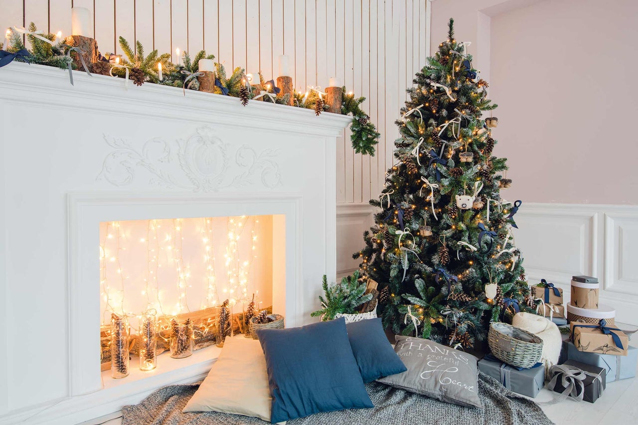 Dekorerad julgran bredvid öppen spis med dekoration och presenter