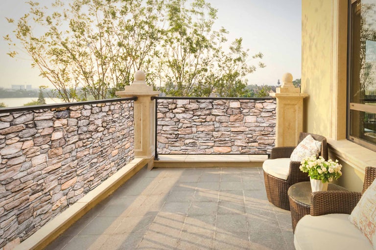 Balkong med stenpaneler som insynsskydd och sittgrupp