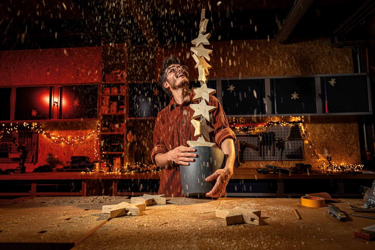 Man i verkstad håller hink med trästjärnor under fallande trädamm