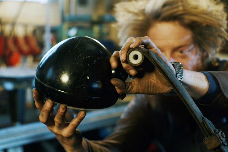 En person håller en svart lampa och en metalldel.