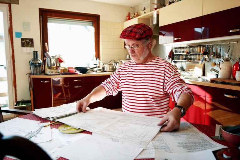Man i köket tittar på ritningar på bordet.