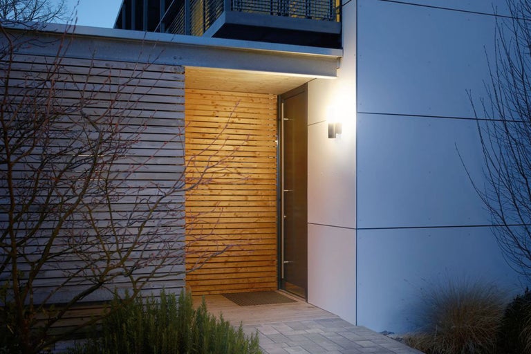 Modern husfasad med träpanel och utomhusbelysning