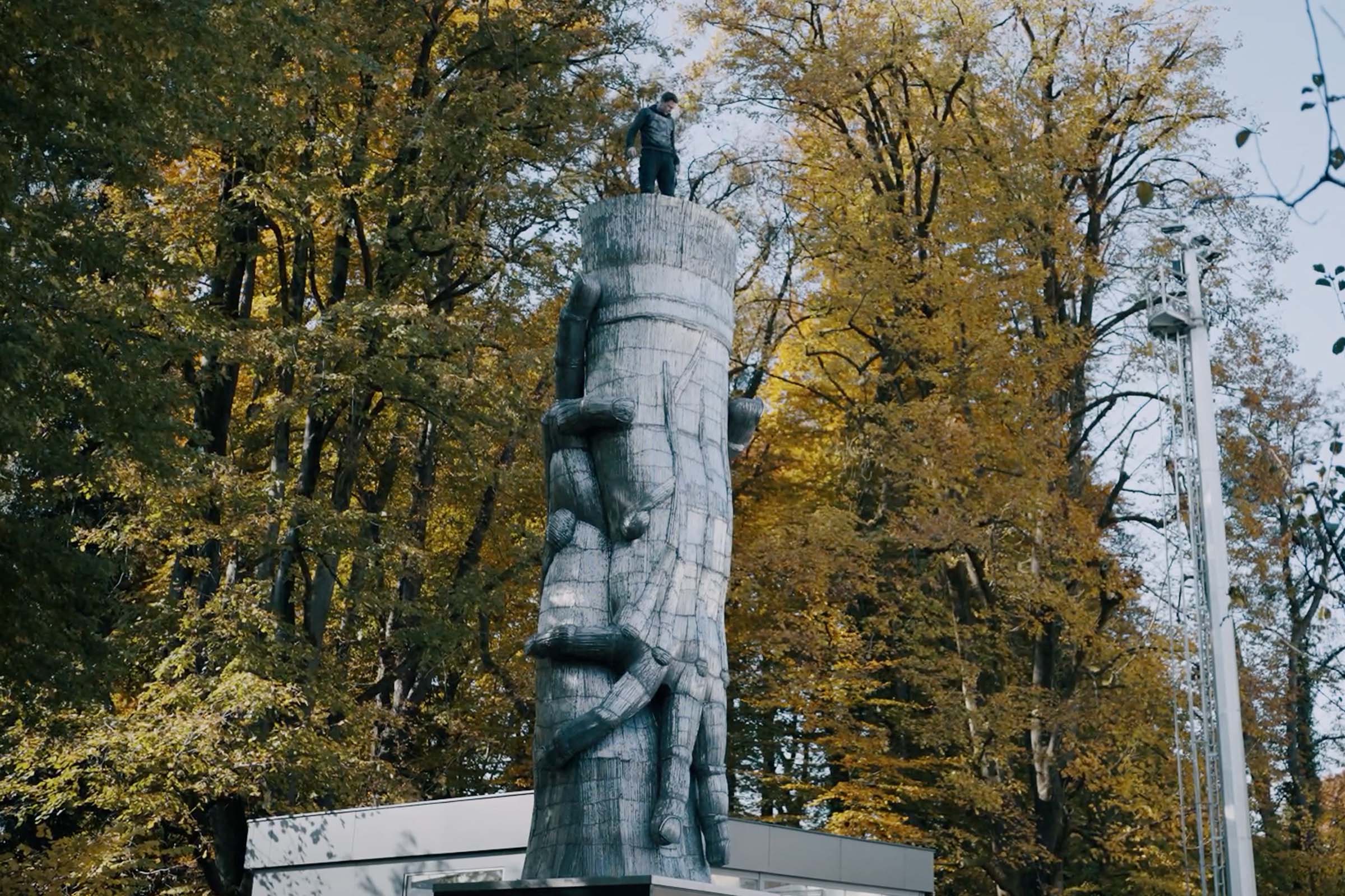 Skulptur av en grupp människor utomhus, omgiven av träd