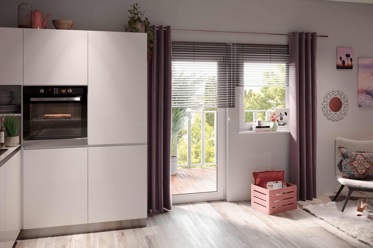 Ljust kök med inbyggnadsugn, fönster mot balkong och dekorationer