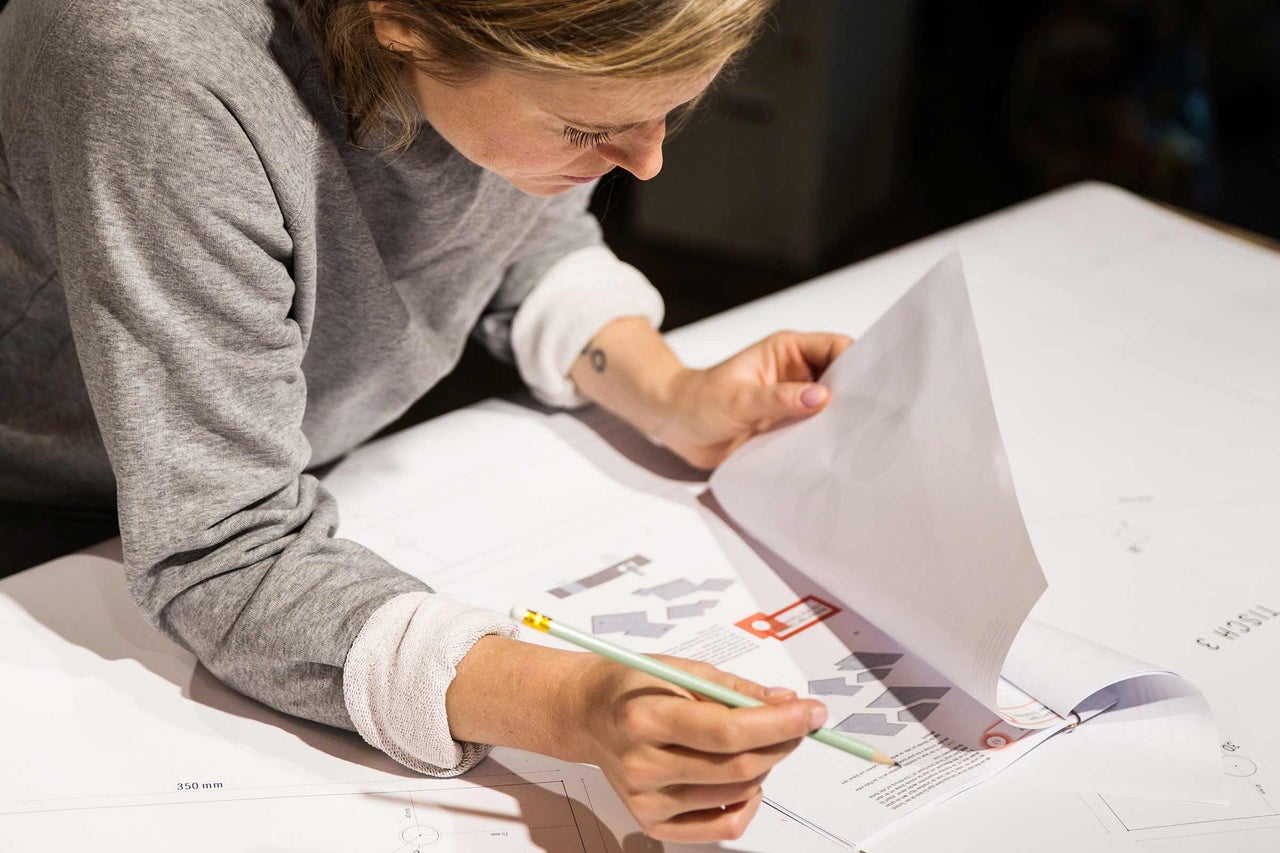 En kvinna tittar på byggplaner med en penna