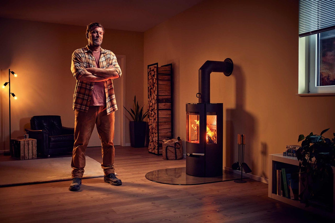 Vardagsrum med vedeldad kamin, vedställ och man