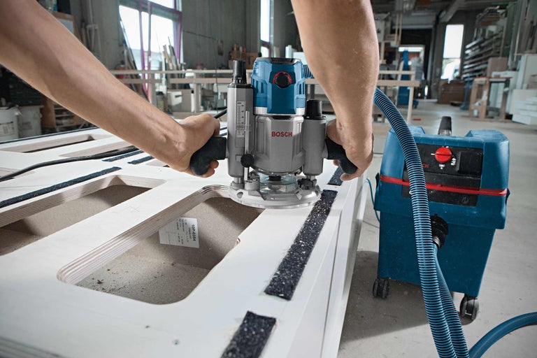 En handöverfräs används på ett arbetsstycke med dammsugare.